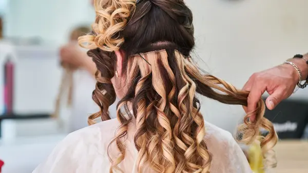 Stylist setting long hair into soft curls at a hairdressing salon
