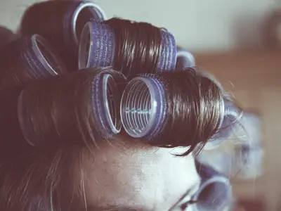 Client's hair wound onto rollers and set during a perm at a salon